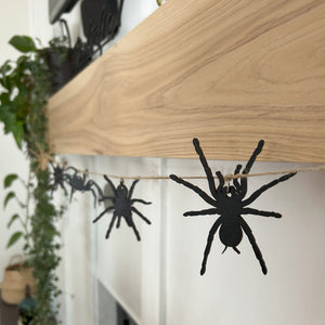 Laser cut spiders strung on a twine string hanging from a wood mantel 