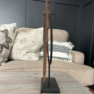 side view of the Little Wreath Stand on a rustic bench. in the background is a beige sofa with pillows in front of black paneling